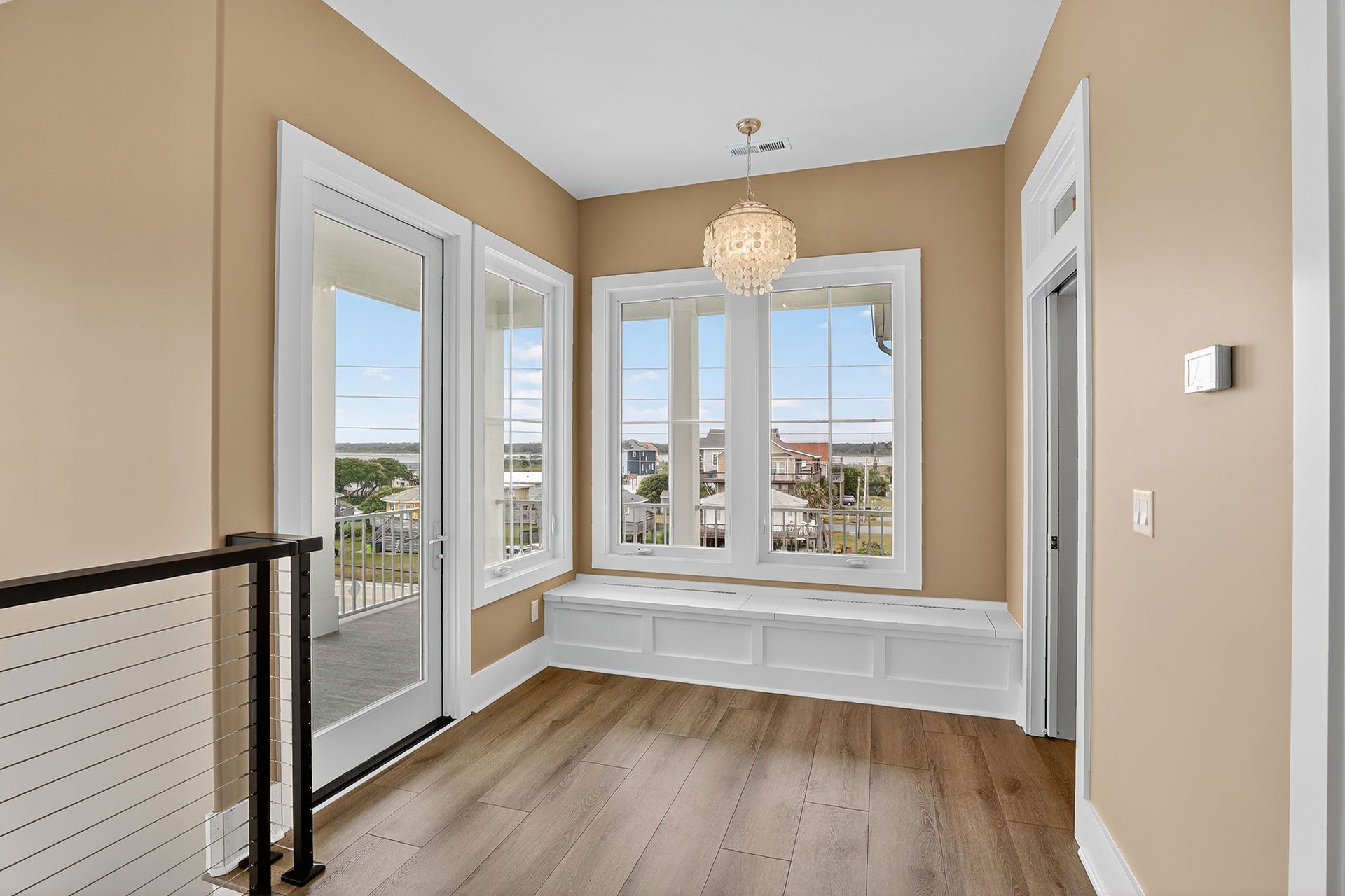 A light-filled room with windows, built-in bench, hardwood floors, and a chandelier.