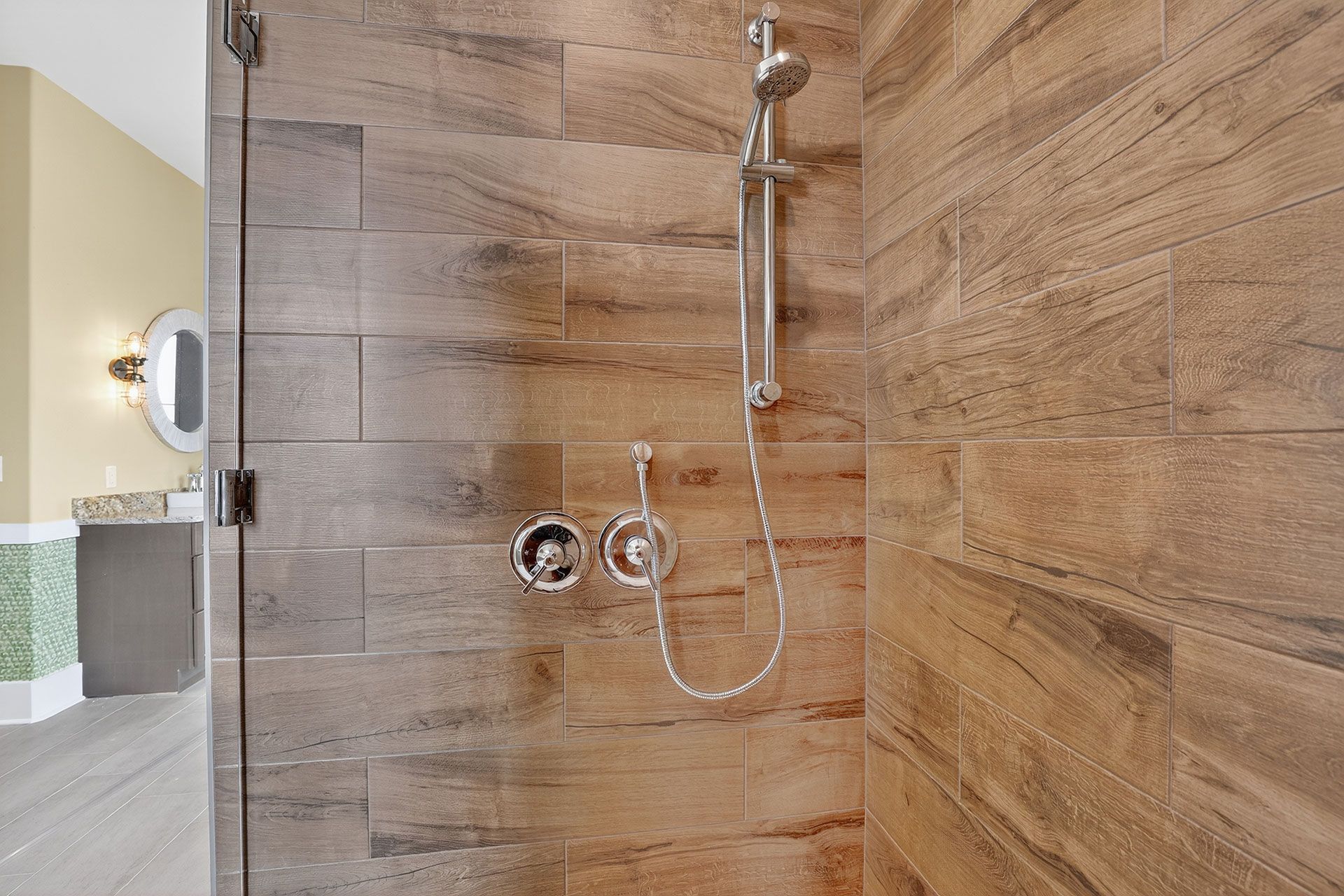 Shower with brown, textured tile walls and silver fixtures.