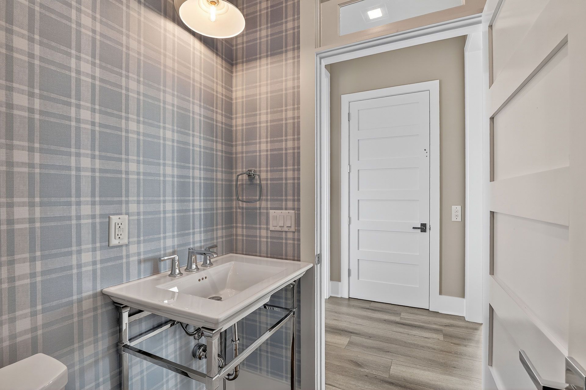 Powder room with plaid wallpaper, sink, and white door.