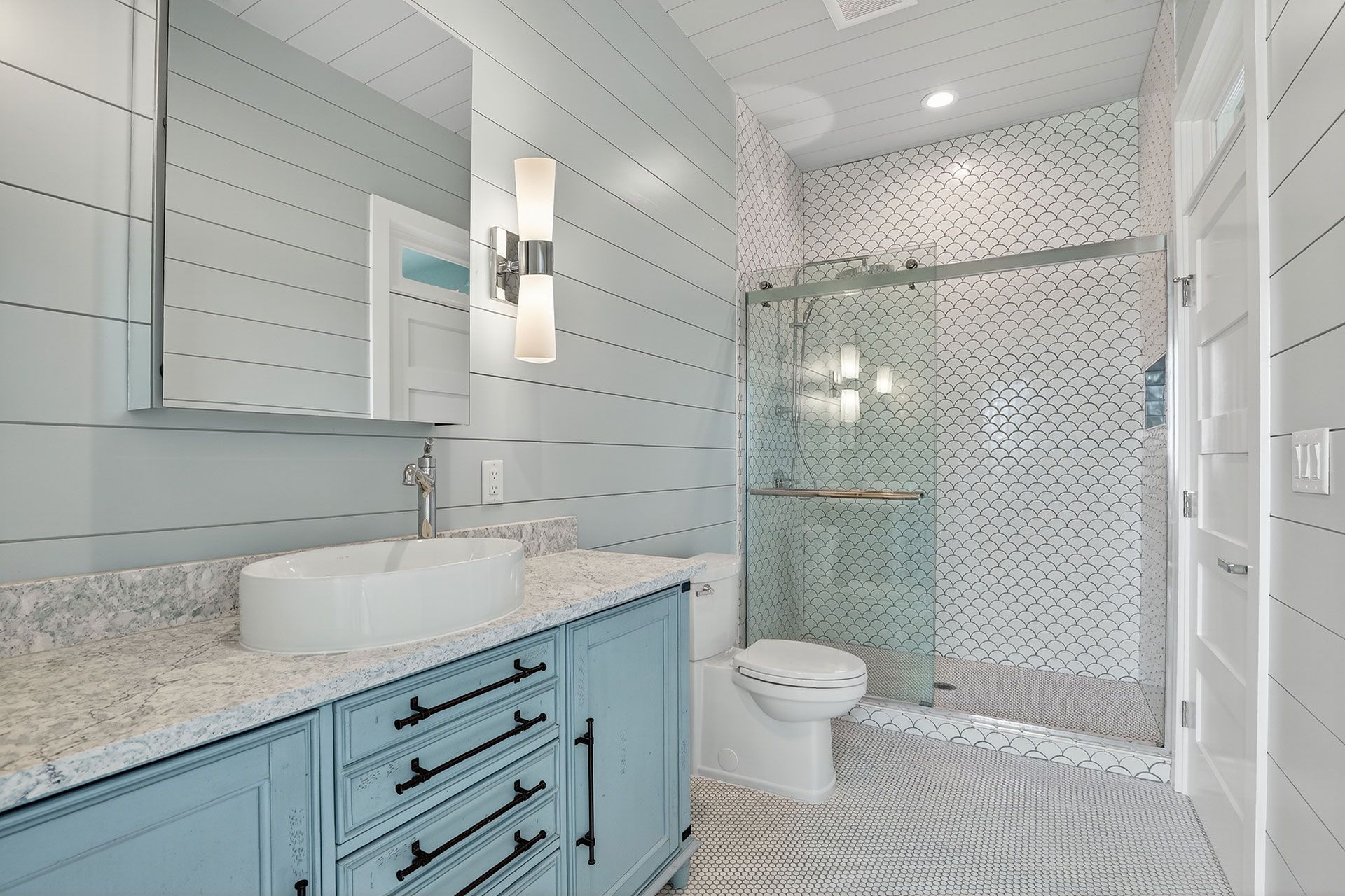 Blue and white bathroom with a vanity, toilet, and shower.