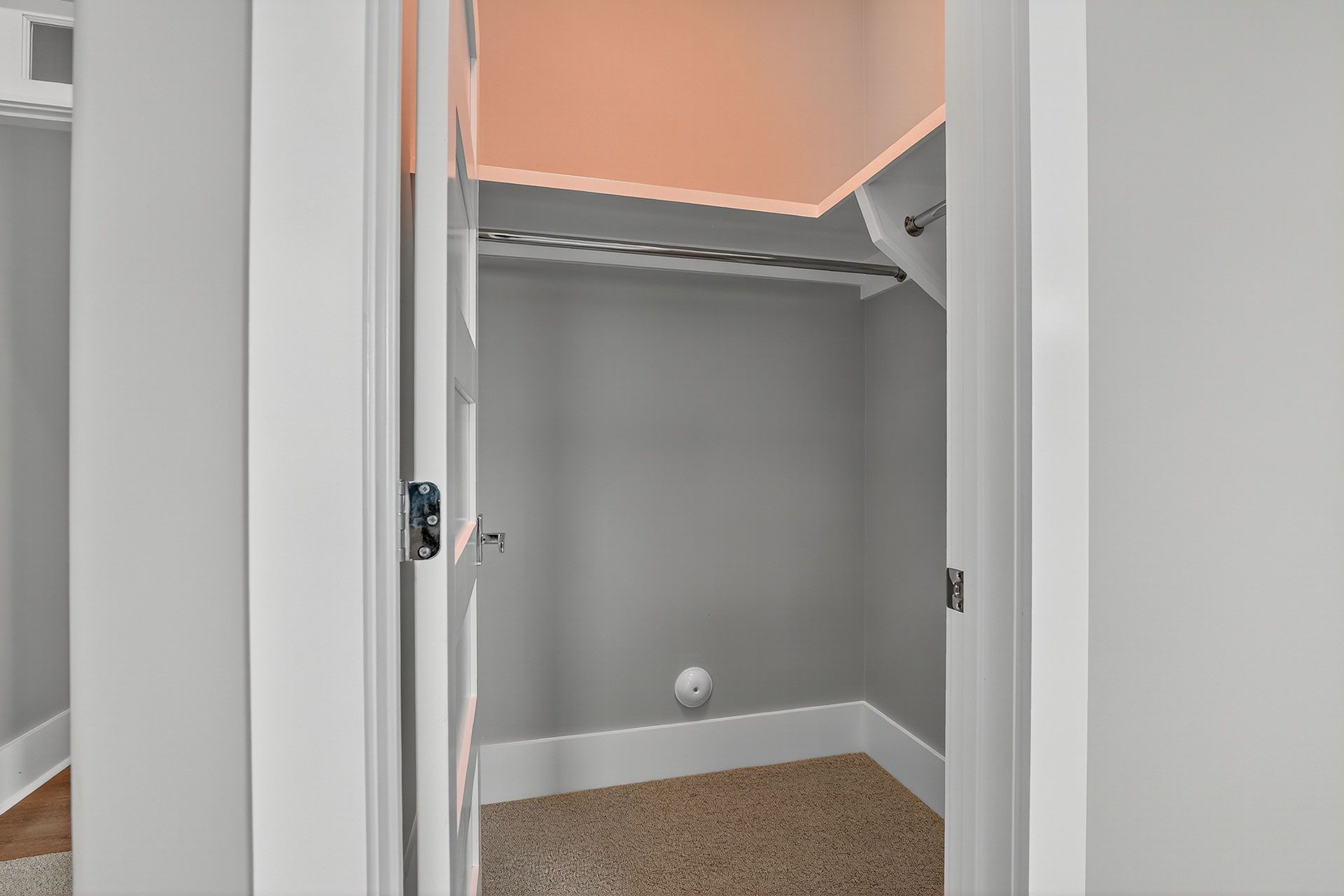 Closet with a clothing rod, gray walls, white trim, and open door.