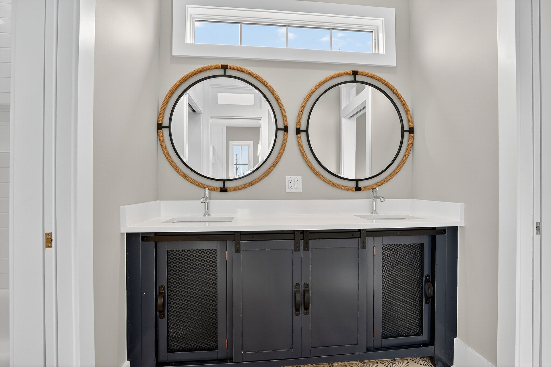 Bathroom with two round mirrors above a black cabinet with sinks.