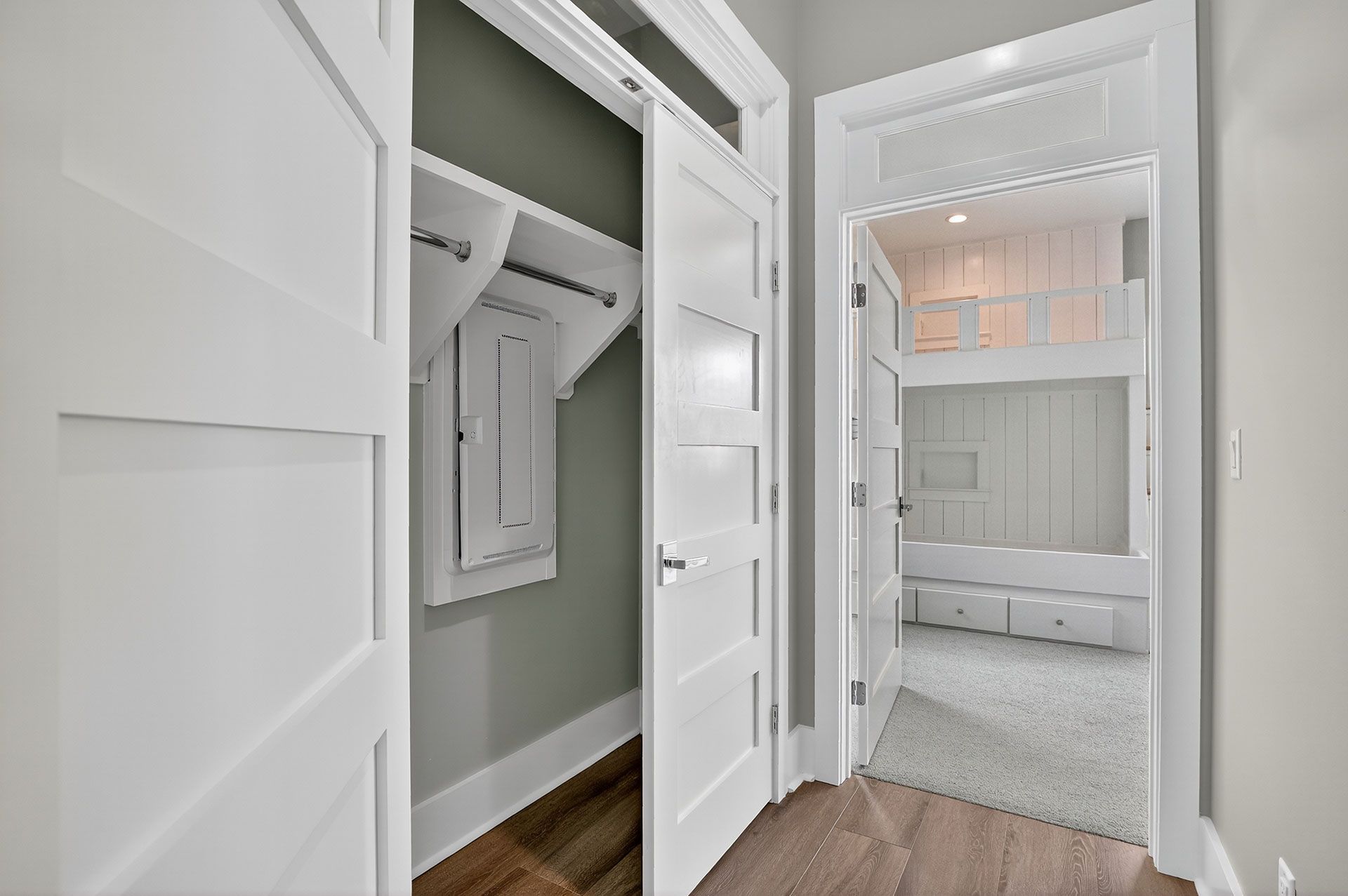 Hallway with white doors, one to a closet with a breaker box, the other to a bunk bed room.
