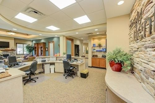 Reception area of a medical office with desks, chairs, and stone accent wall.