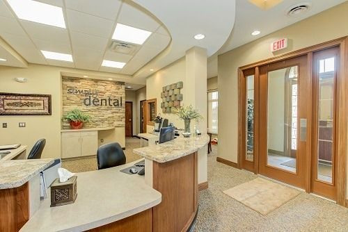 Reception area of a dental office with front desk, sign, and exit doors.