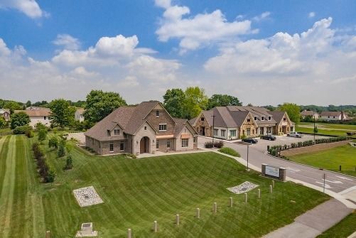 Large brick house with manicured lawn and another building on a sunny day.