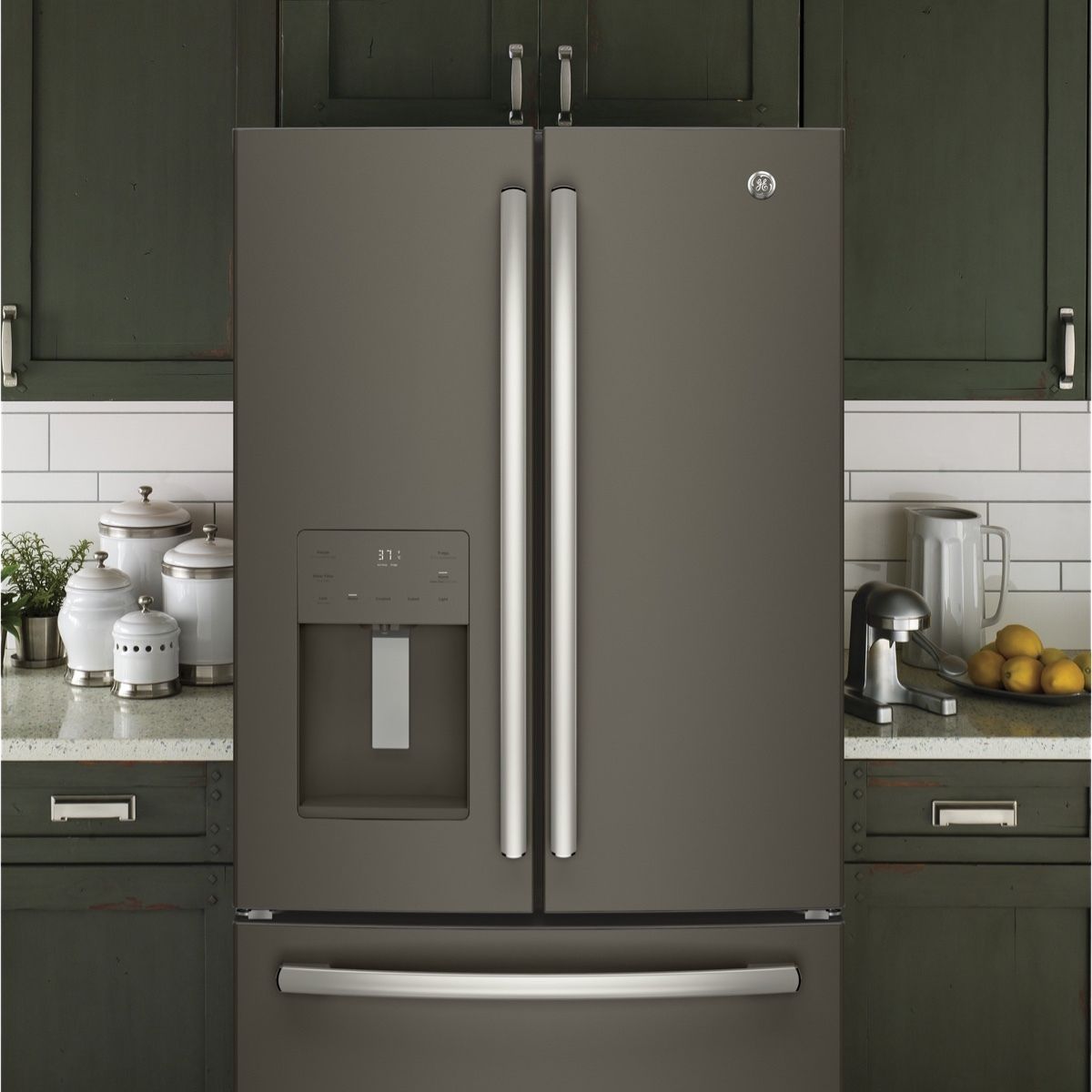A gray refrigerator is in a kitchen with green cabinets.