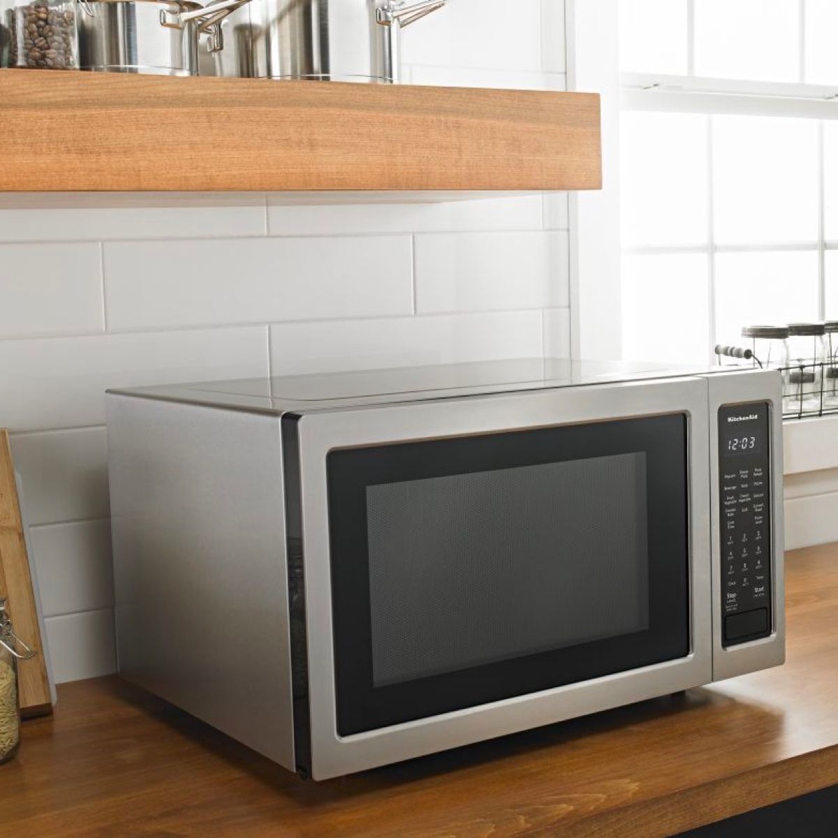 A microwave oven is sitting on a wooden counter in a kitchen.