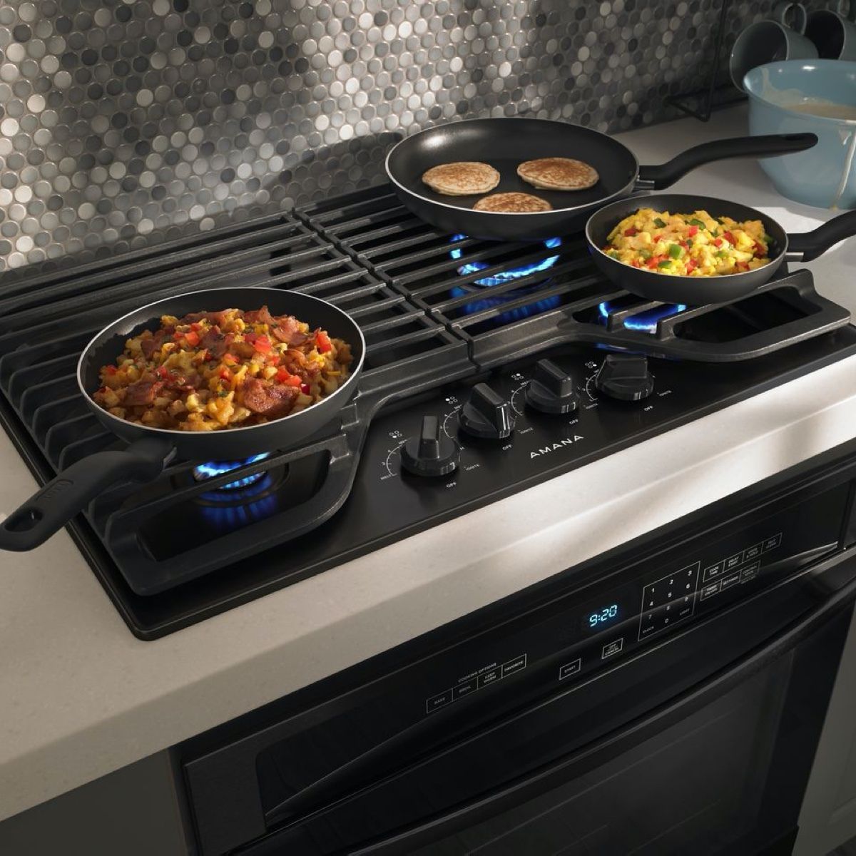 Three pans of food are cooking on a gas stove