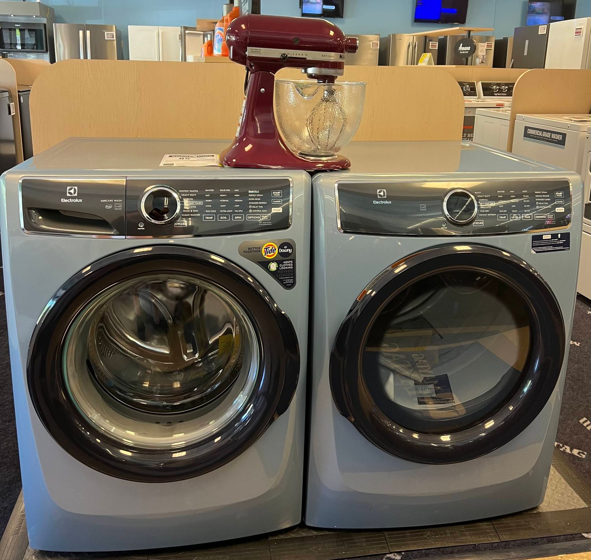 A kitchenaid mixer sits on top of a washer and dryer