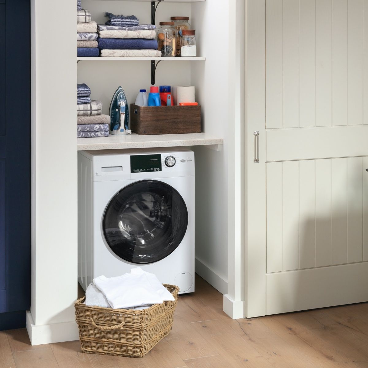A laundry room with a washer and dryer and a basket of clothes