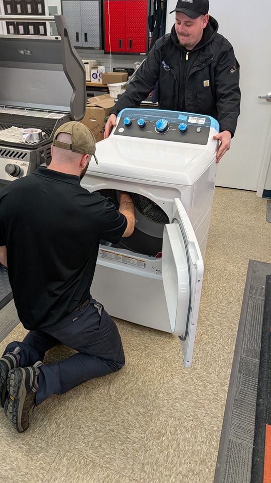 Two men are working on a washing machine and dryer in a kitchen.