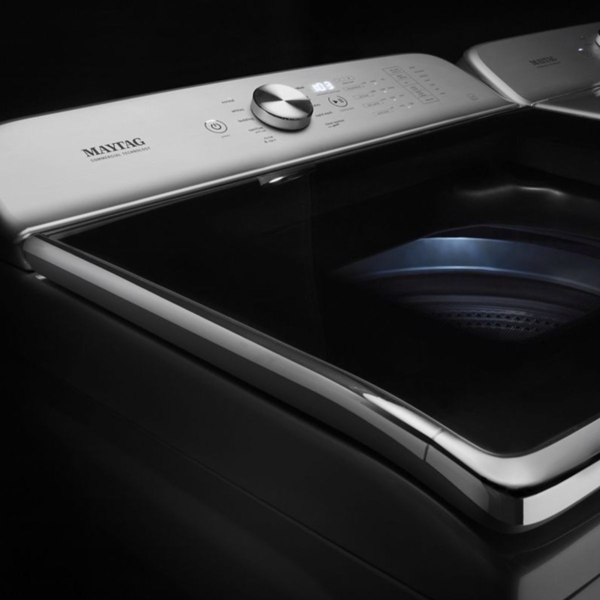 A maytag washing machine is sitting on a black surface