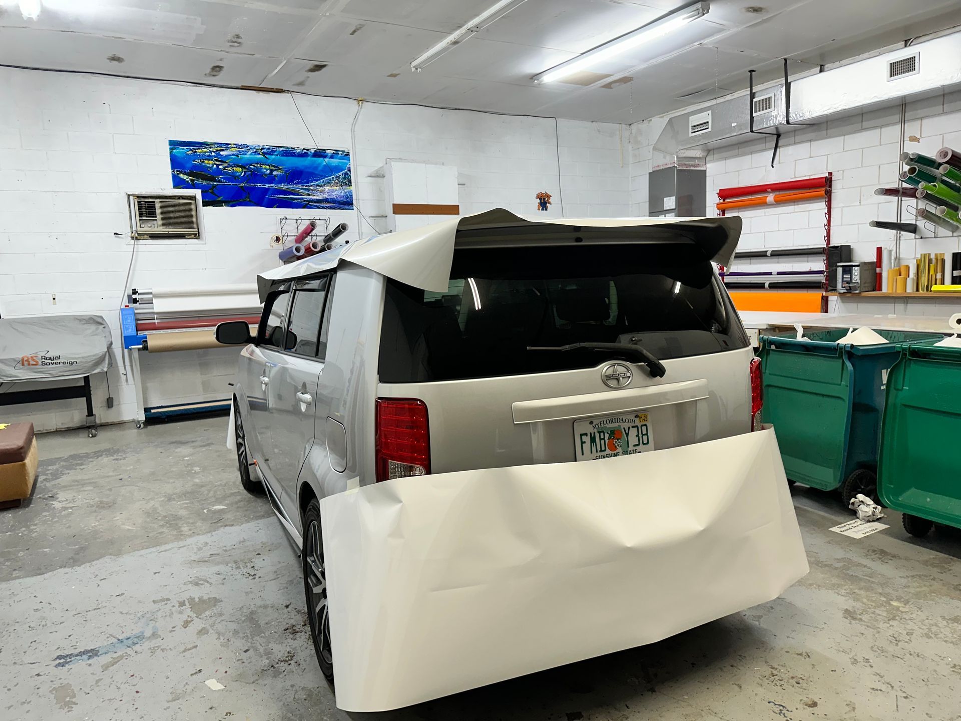 Silver SUV in a workshop with its rear bumper removed, surrounded by tools and equipment