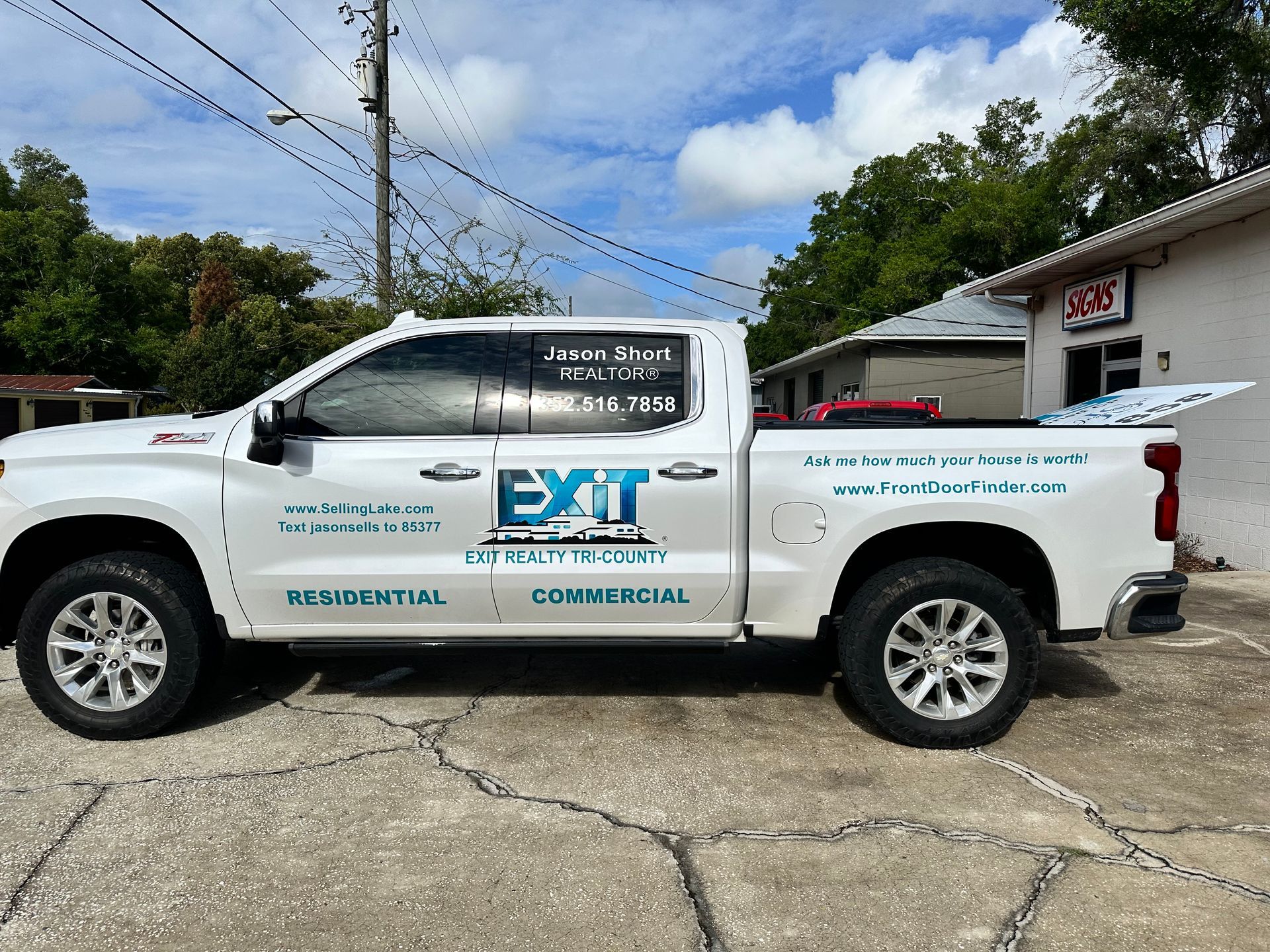 White EXIT Realty SUV parked outdoors with company branding on the side