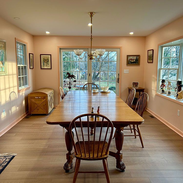 Dining room with pink walls, wooden table, and chairs, and a glass door to the outside.