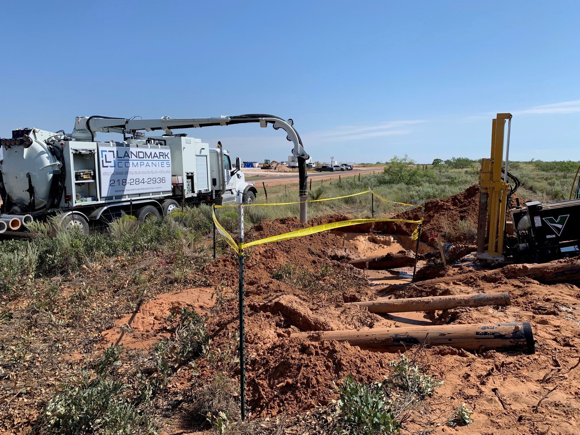 a vacuum truck is driving through a dirt field .
