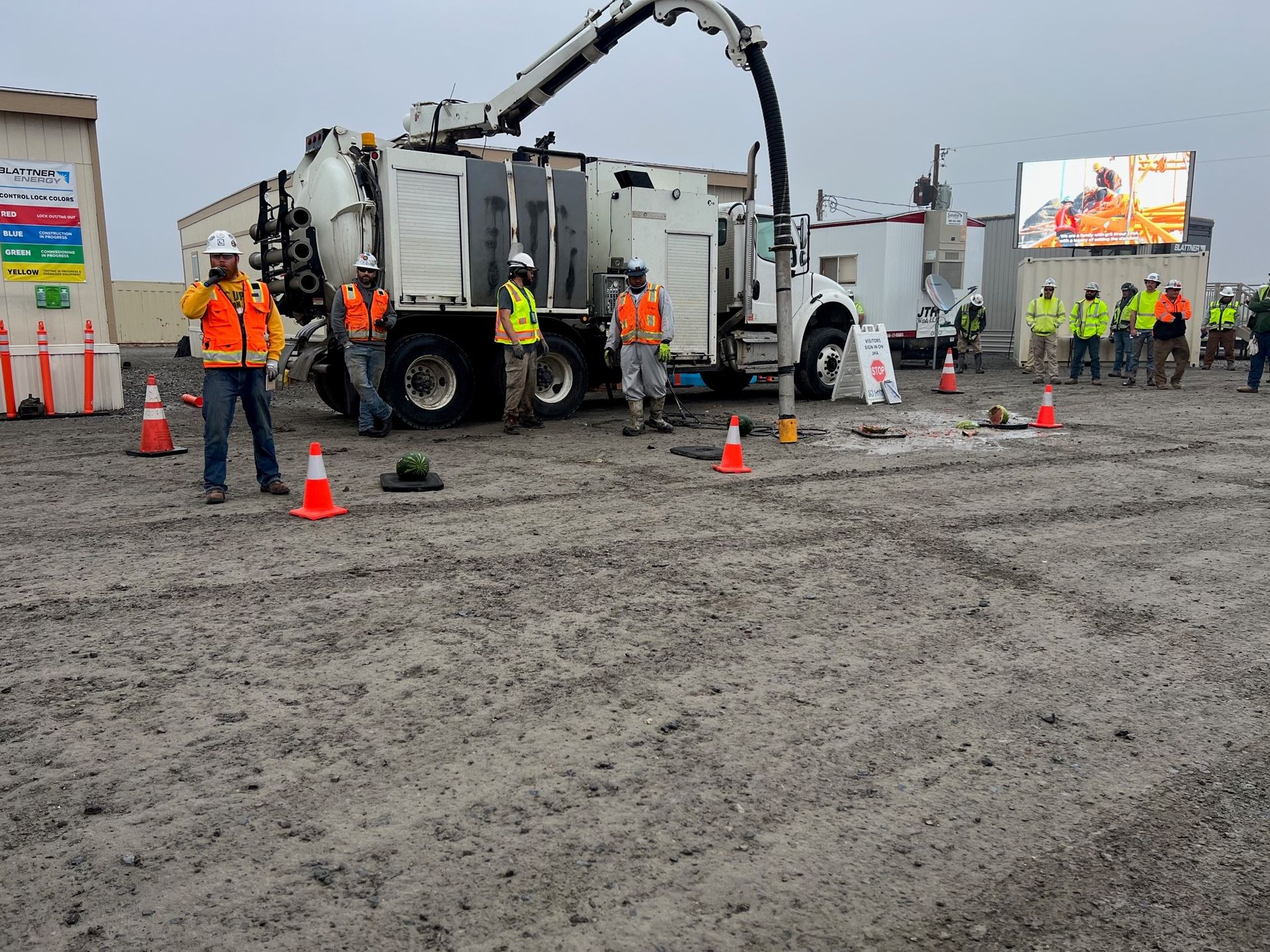 a group of construction workers are standing in front of a vacuum truck .