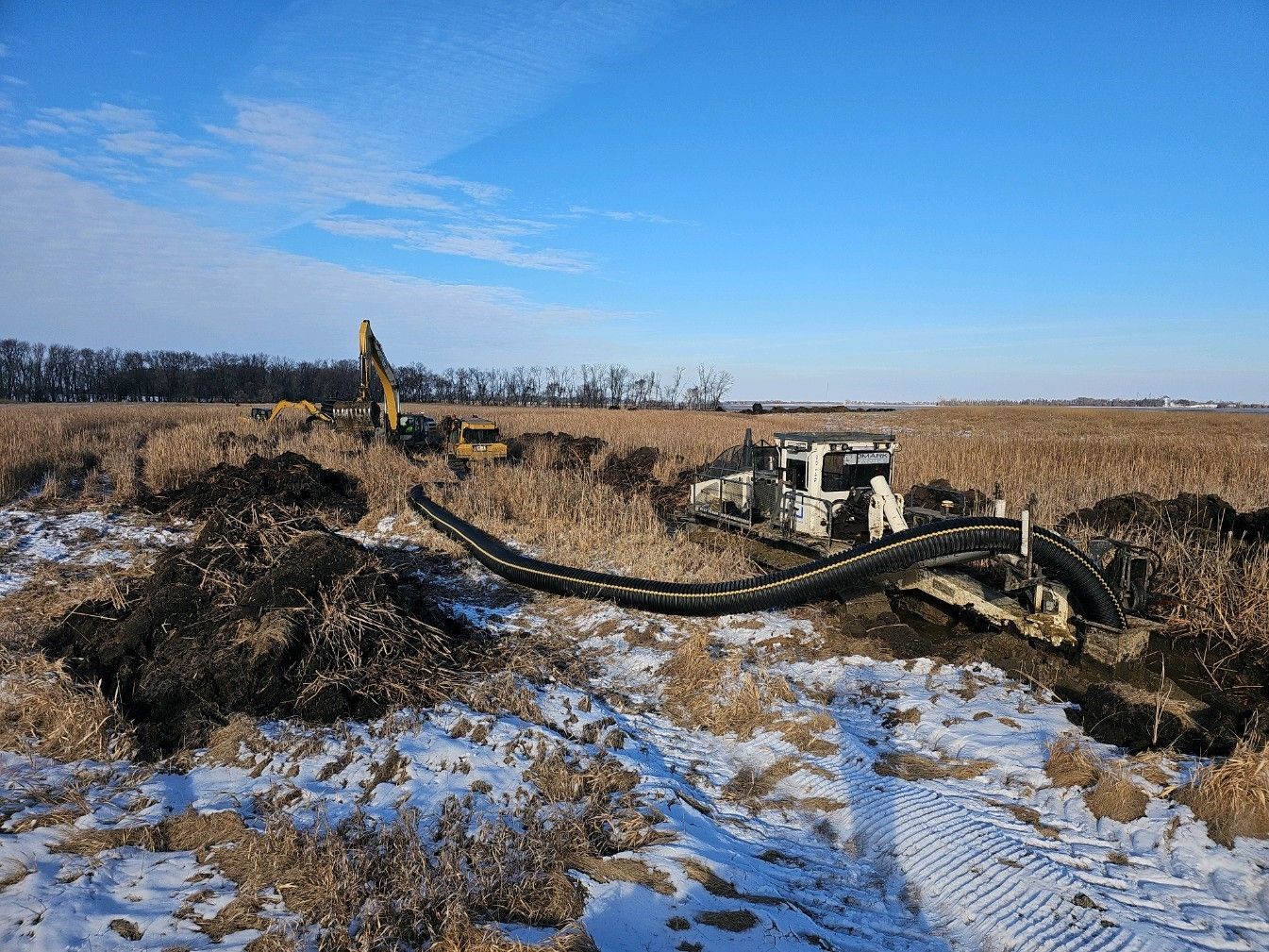 A bulldozer is digging a hole in a snowy field.