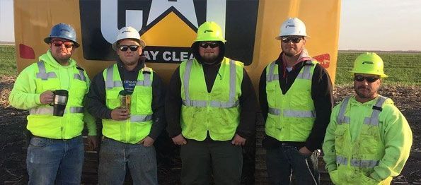 A group of construction workers are standing in front of a cat truck