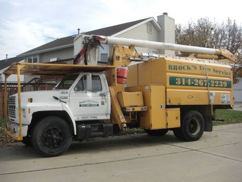 Yellow utility truck with bucket lift parked on a residential street