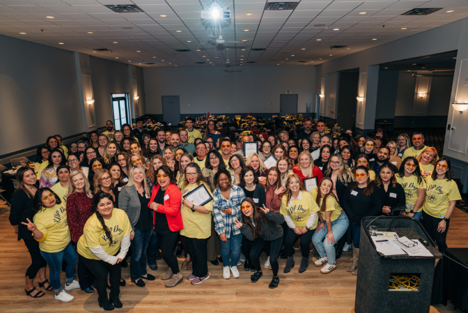 A large group of people are posing for a picture in a room.