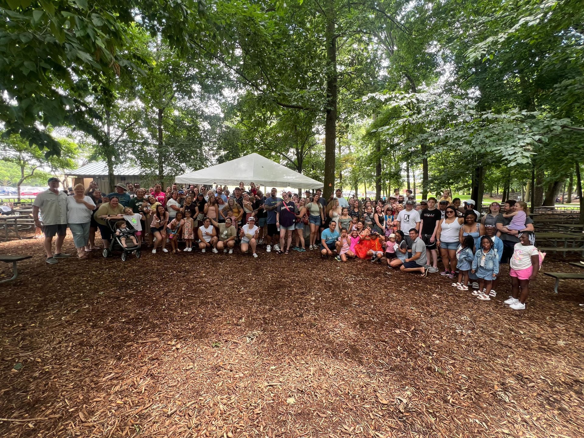 A large group of people are posing for a picture in a park.