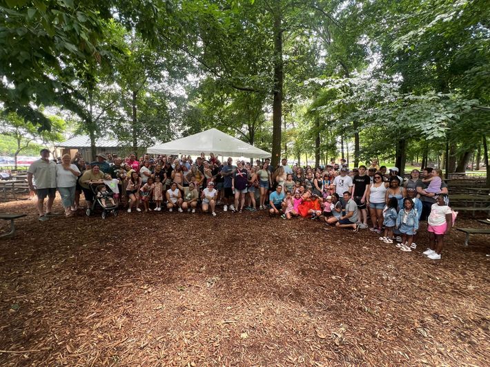 A large group of people are posing for a picture in a park.