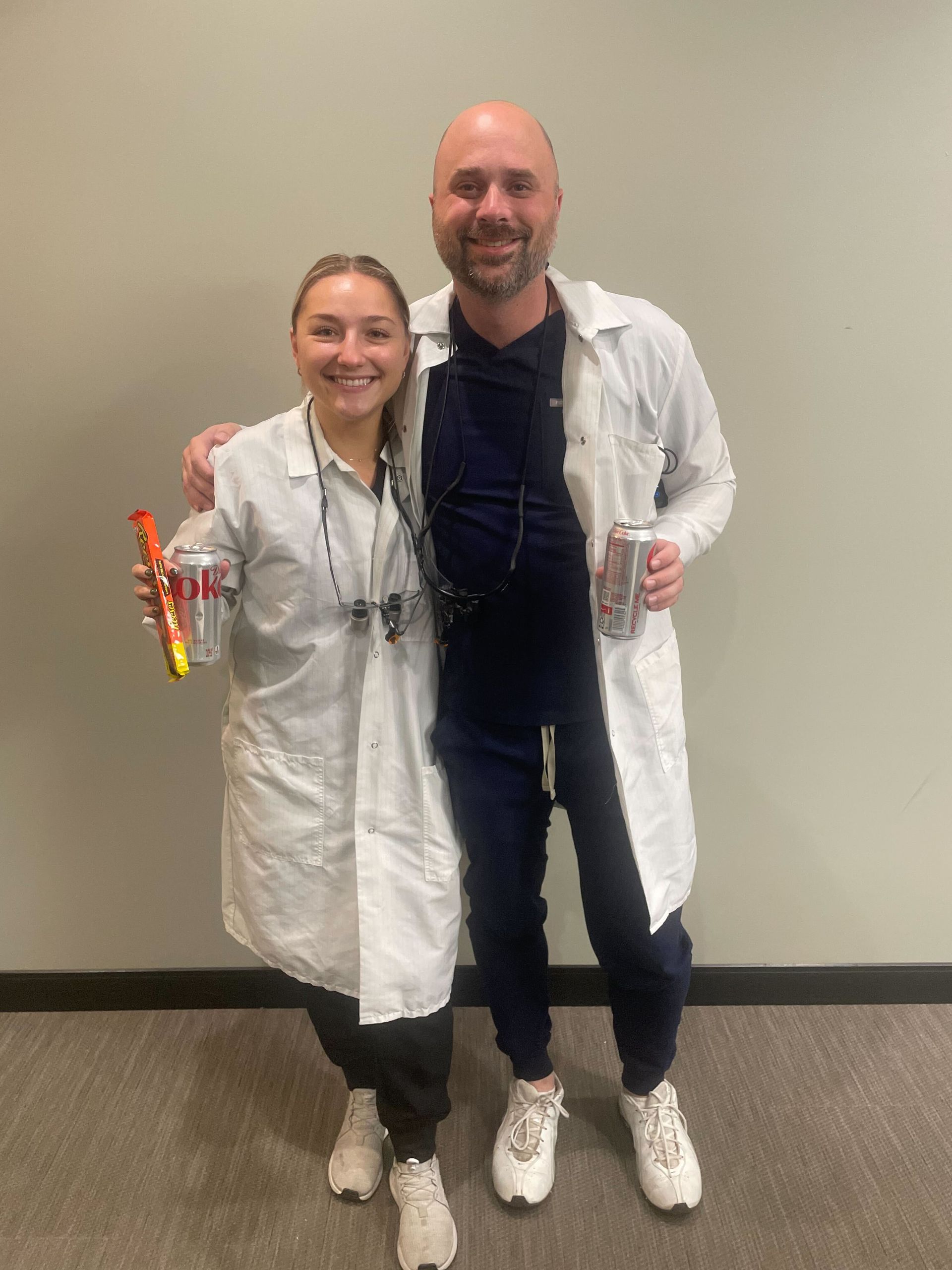 A man and a woman in lab coats are standing next to each other.