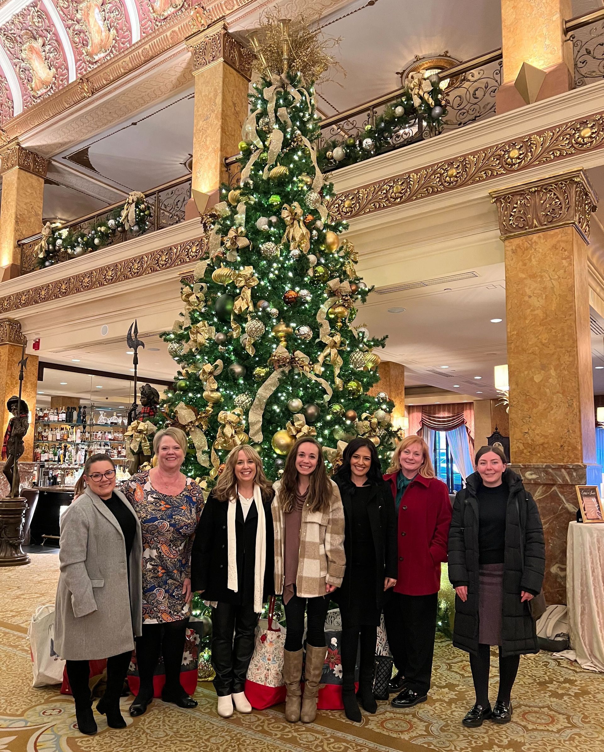 A group of women are posing for a picture in front of a christmas tree.