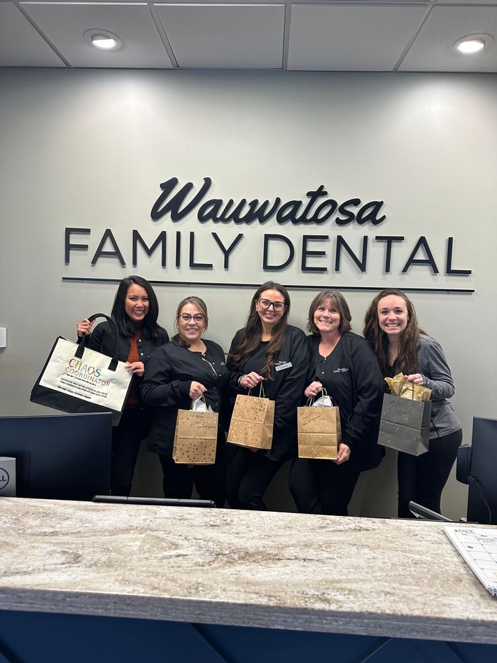 A woman is holding a cup of coffee in front of a sign that says welcome to bay view dental care.