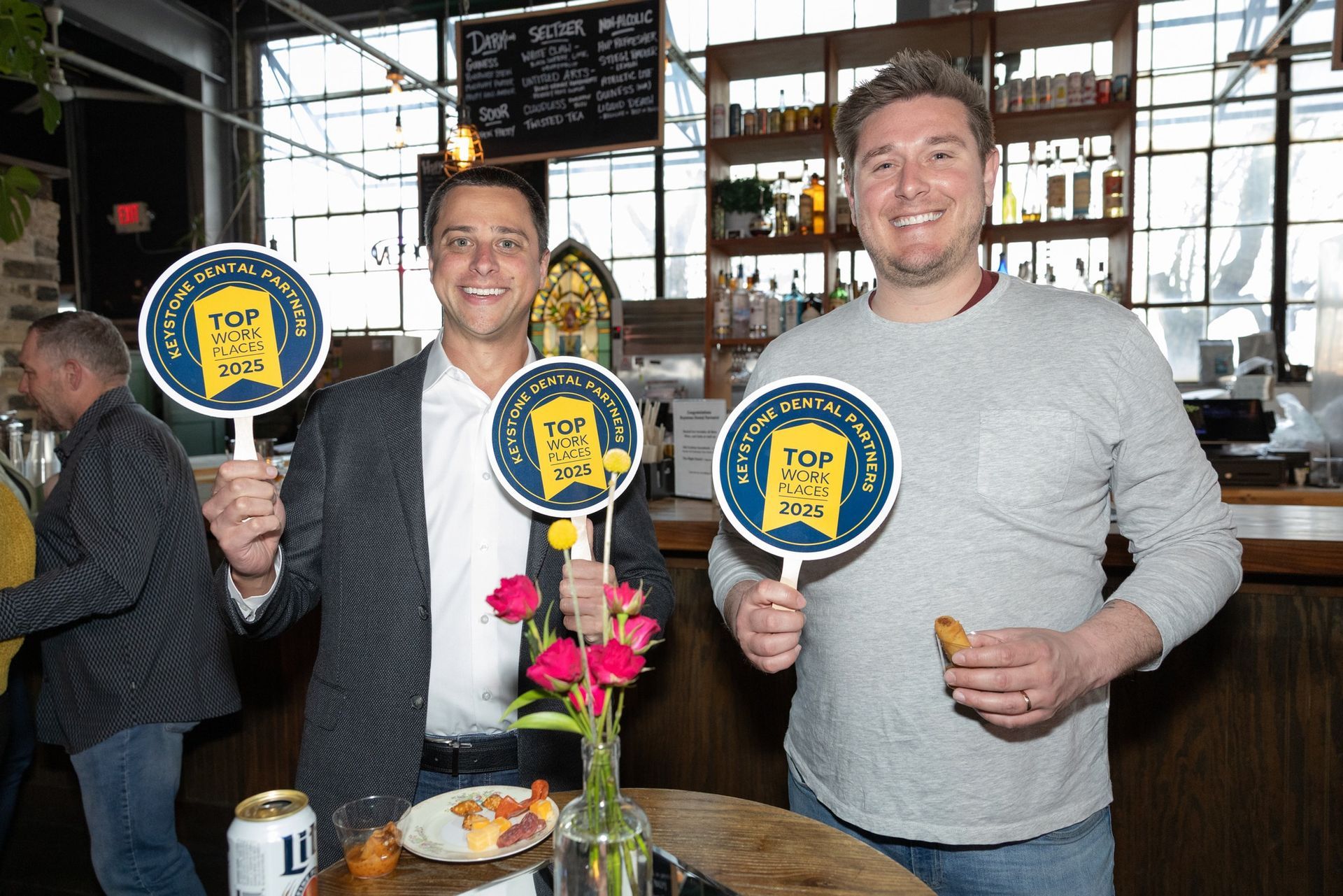 Two men are standing next to each other holding signs in a restaurant.