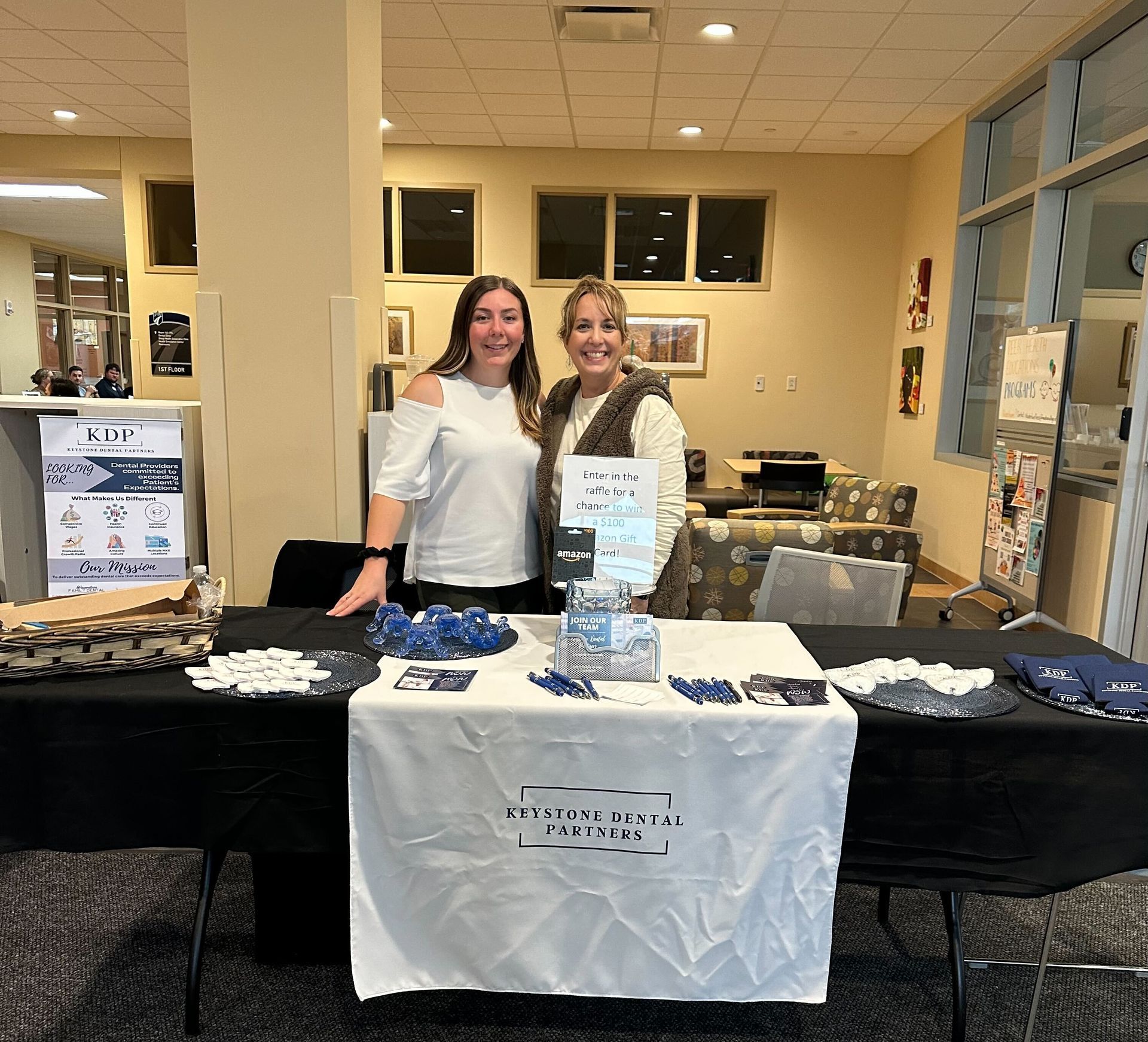 Two women standing in front of a table that says priority