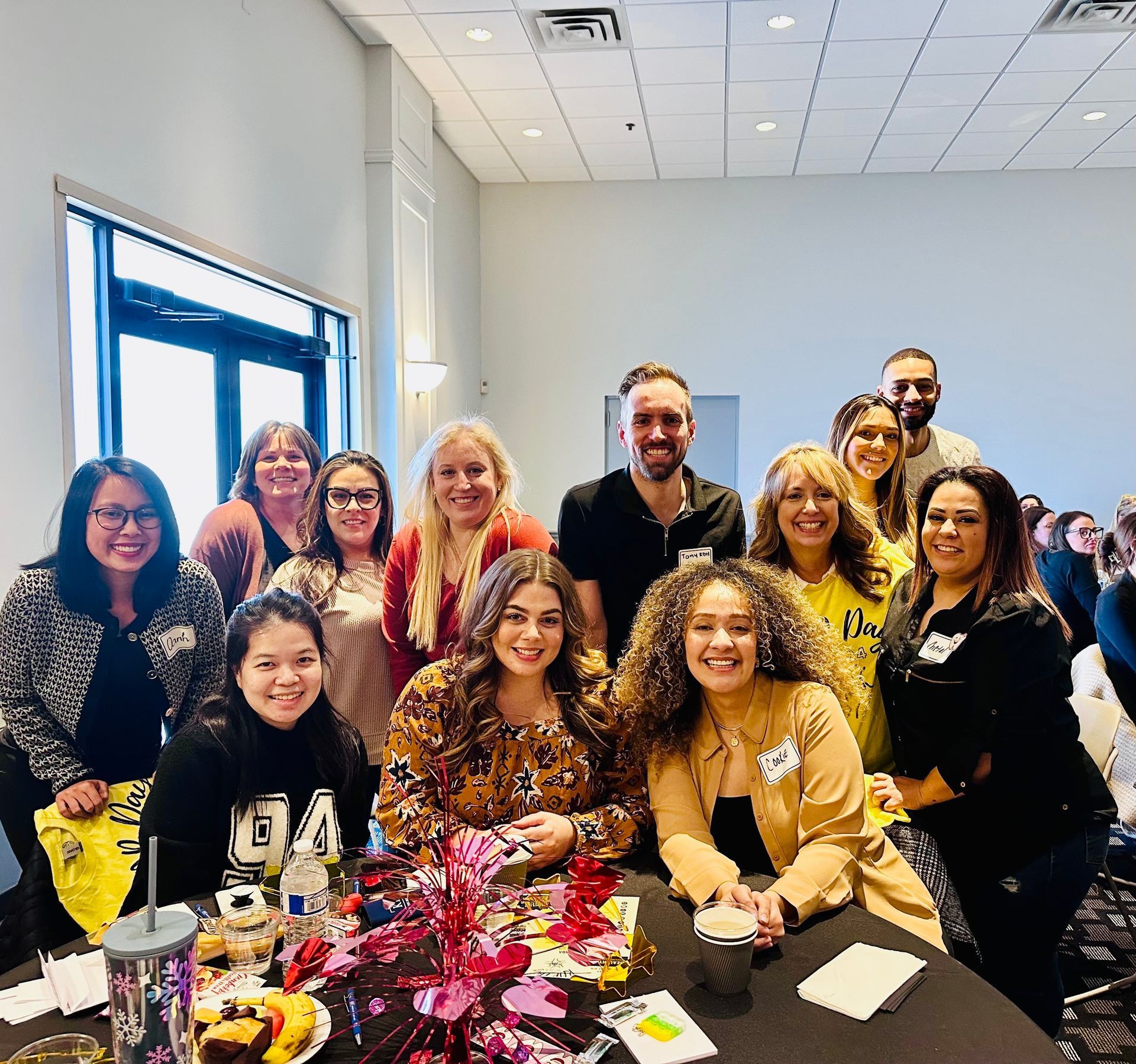 A group of people are posing for a picture while sitting at a table.