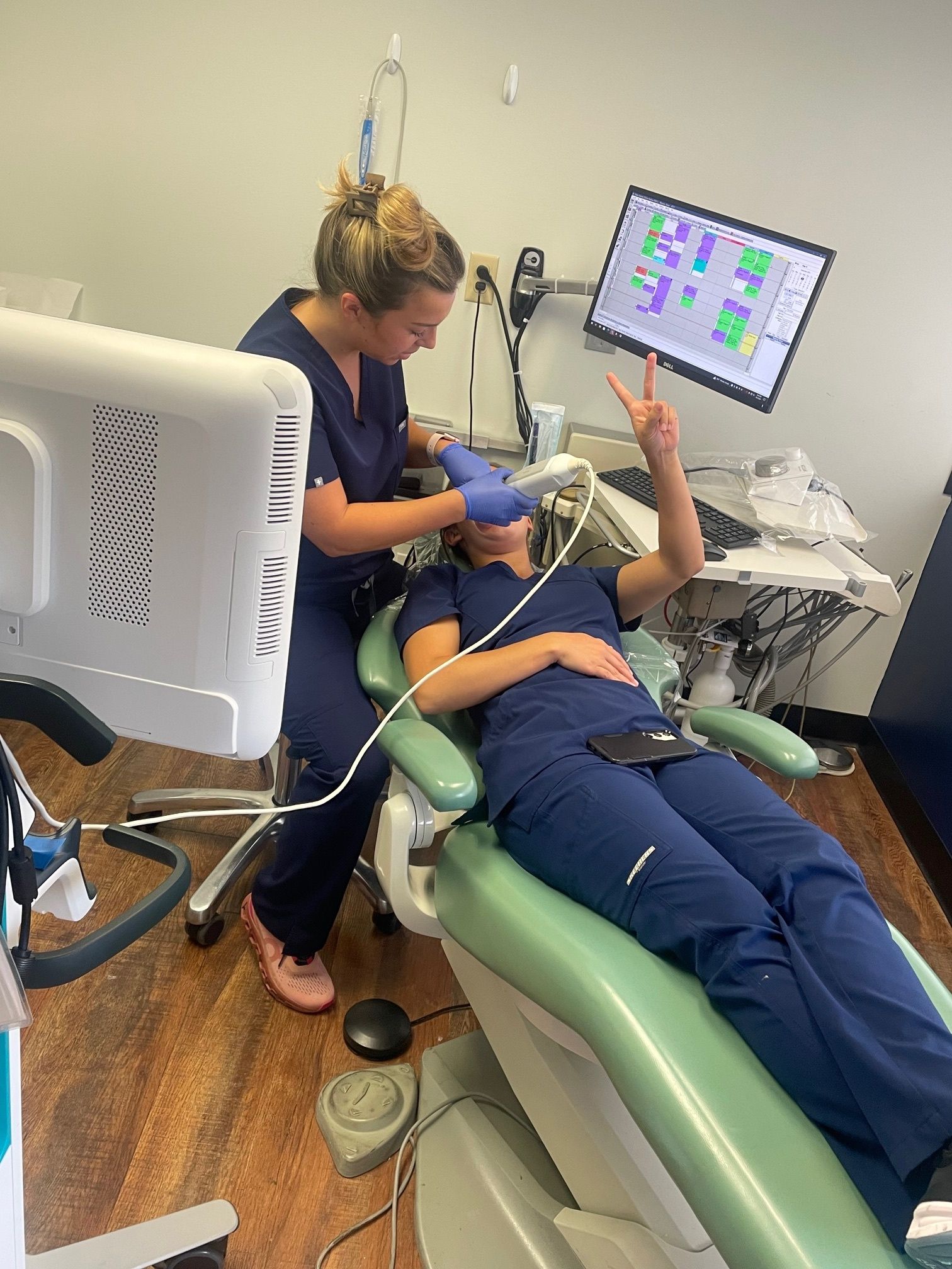 A woman is laying in a dental chair while a nurse looks on.