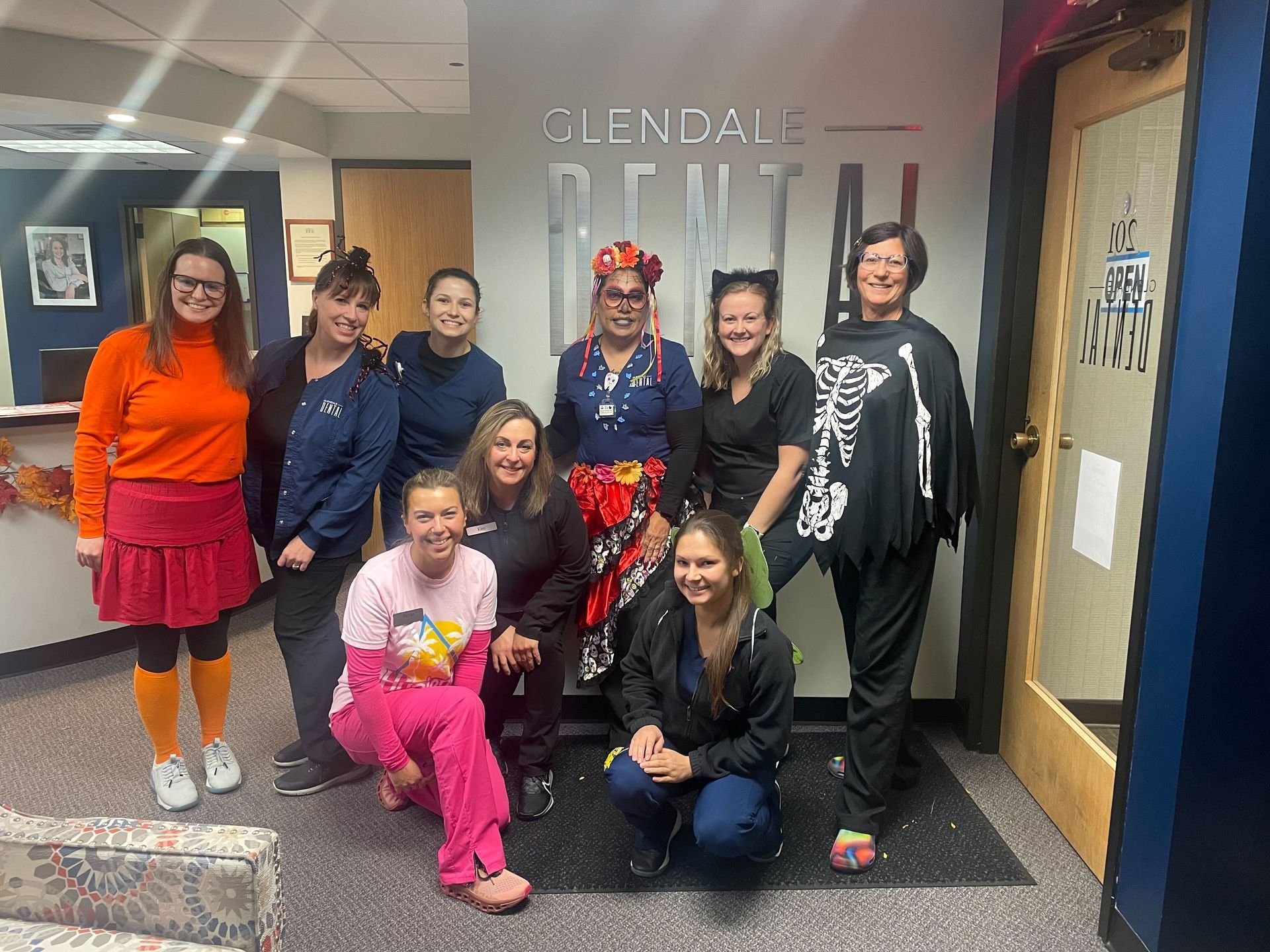 A group of women are posing for a picture in front of a dental office.