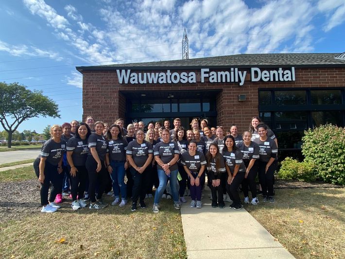 A large group of people are posing for a picture in front of a dental office