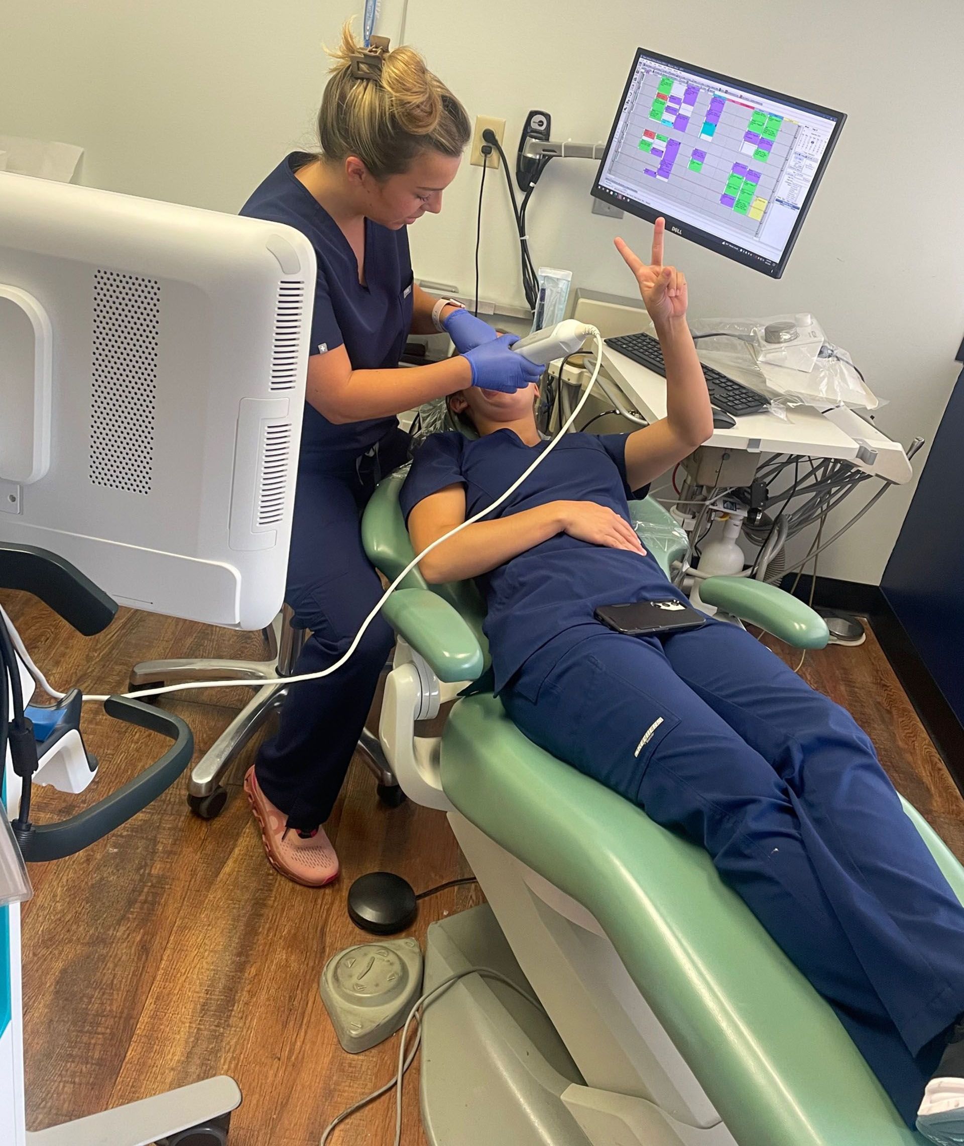 A woman is laying in a dental chair while a nurse looks on