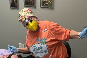 a woman wearing a free dental day shirt is sitting in a dental chair with a patient