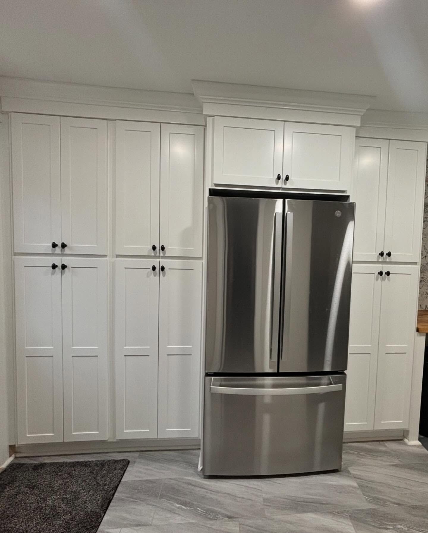 A kitchen with white cabinets and a stainless steel refrigerator.