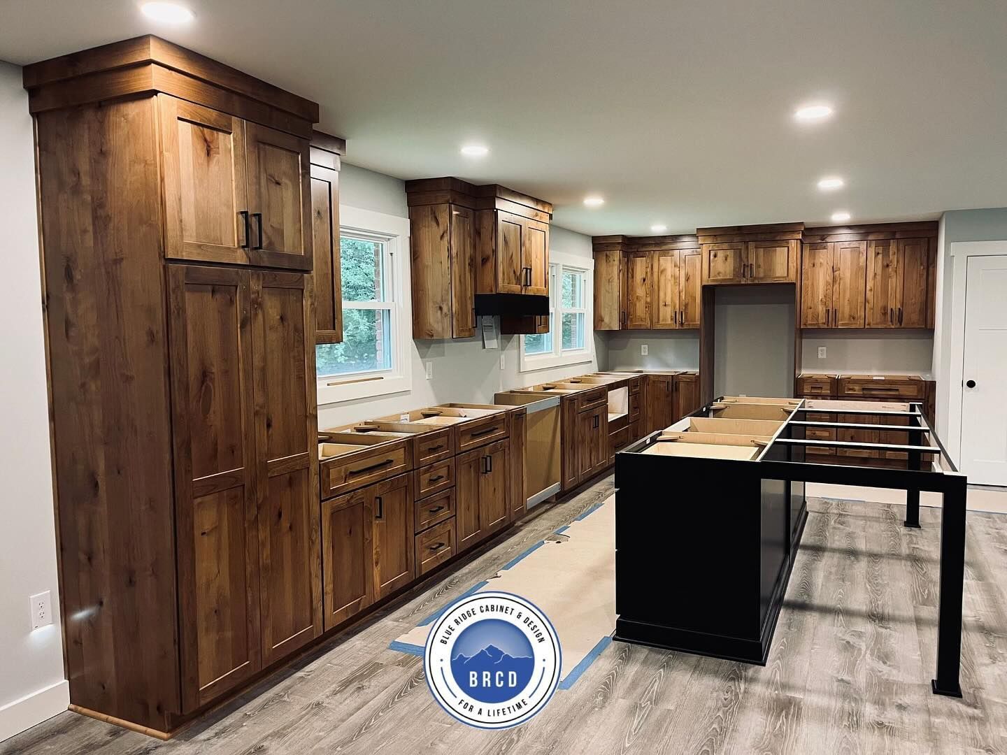 A kitchen with wooden cabinets and a black island.