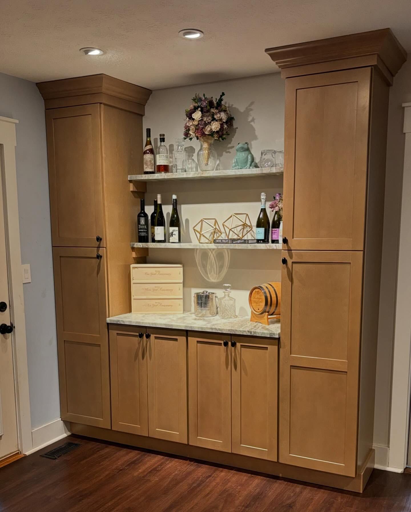 A kitchen with wooden cabinets and shelves filled with bottles of wine.