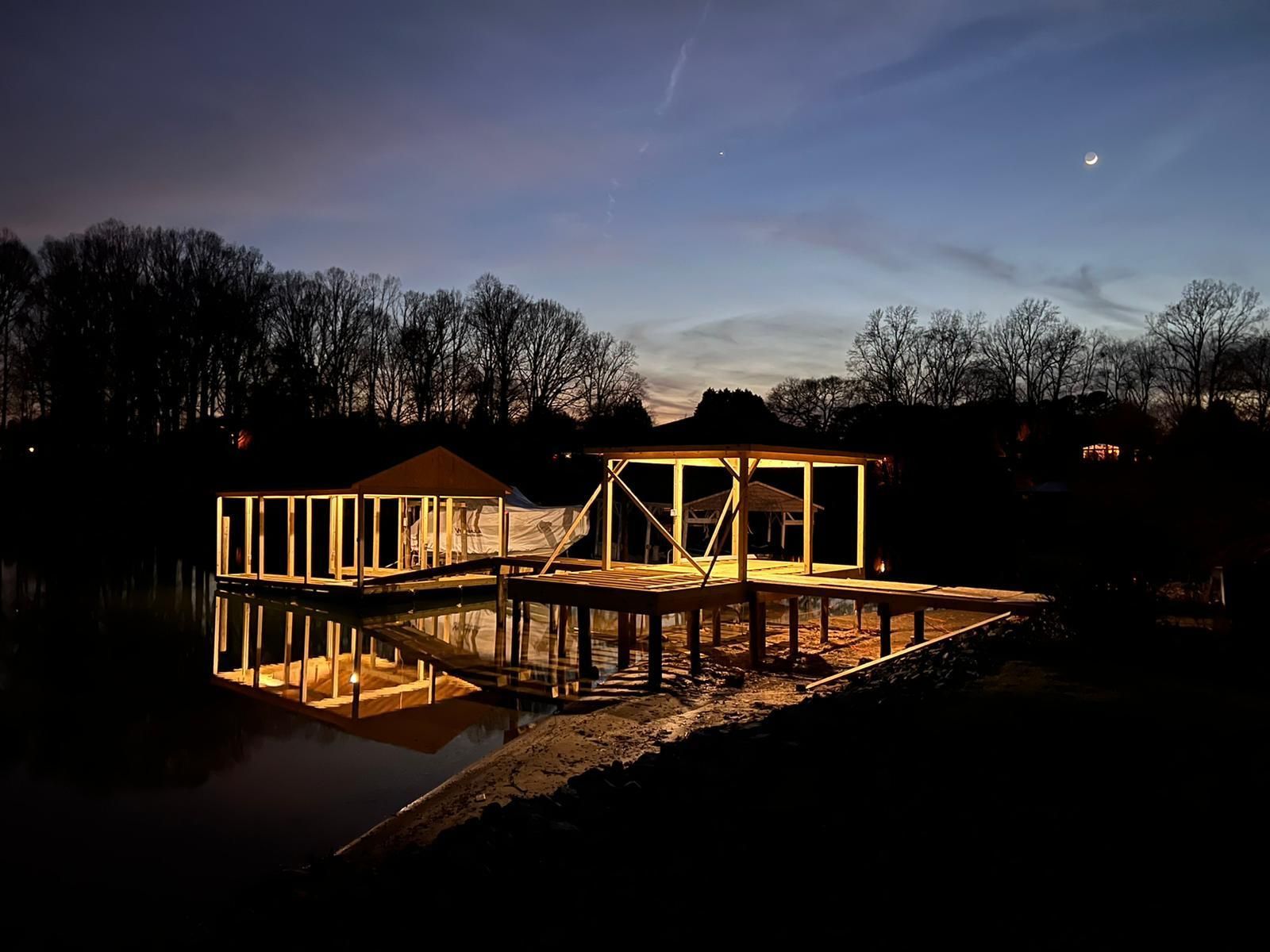 A house is being built next to a body of water at night.