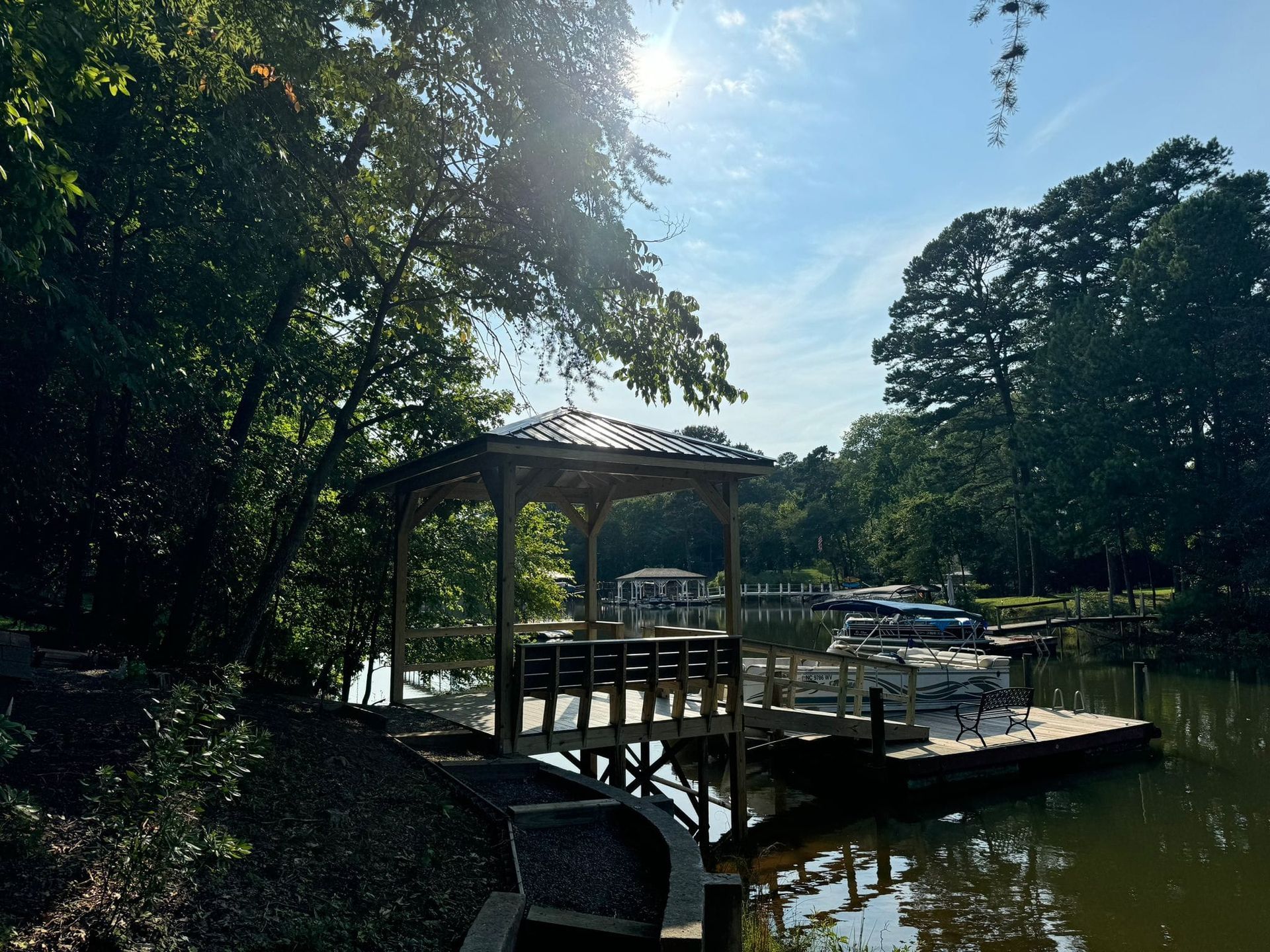 A dock with a gazebo overlooking a body of water surrounded by trees.