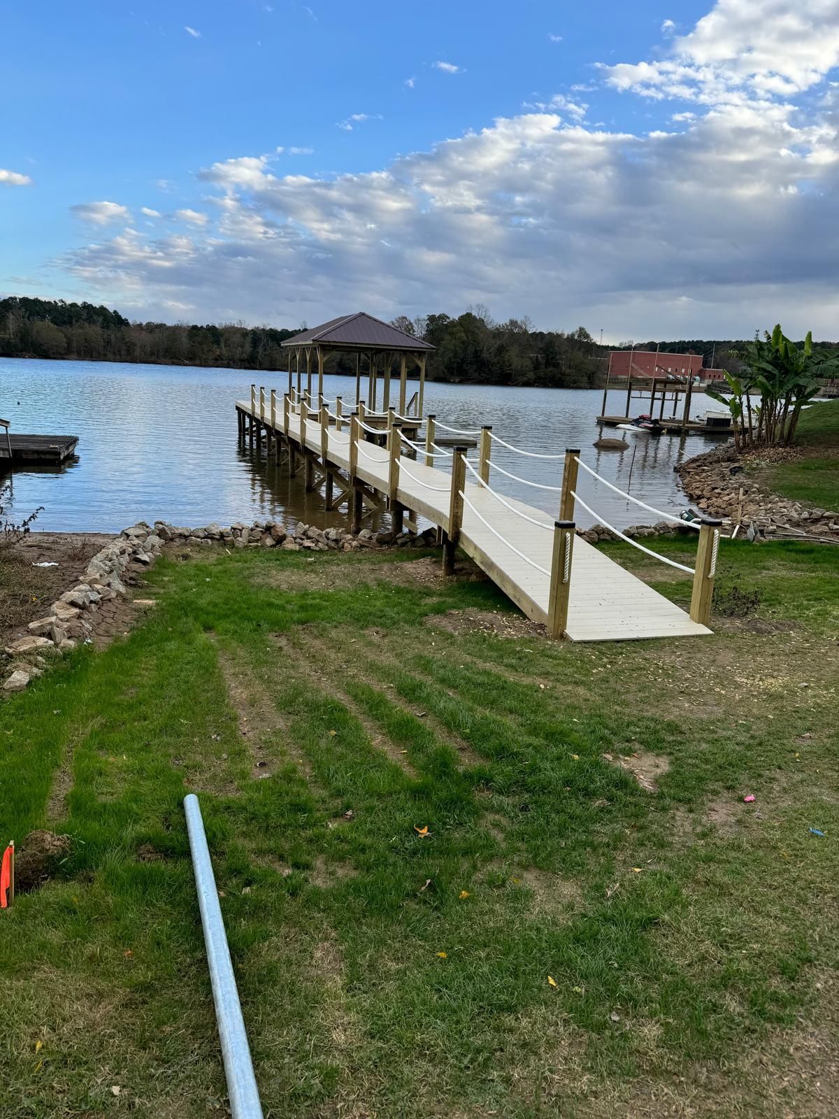 A dock with a ramp leading to it is next to a lake.