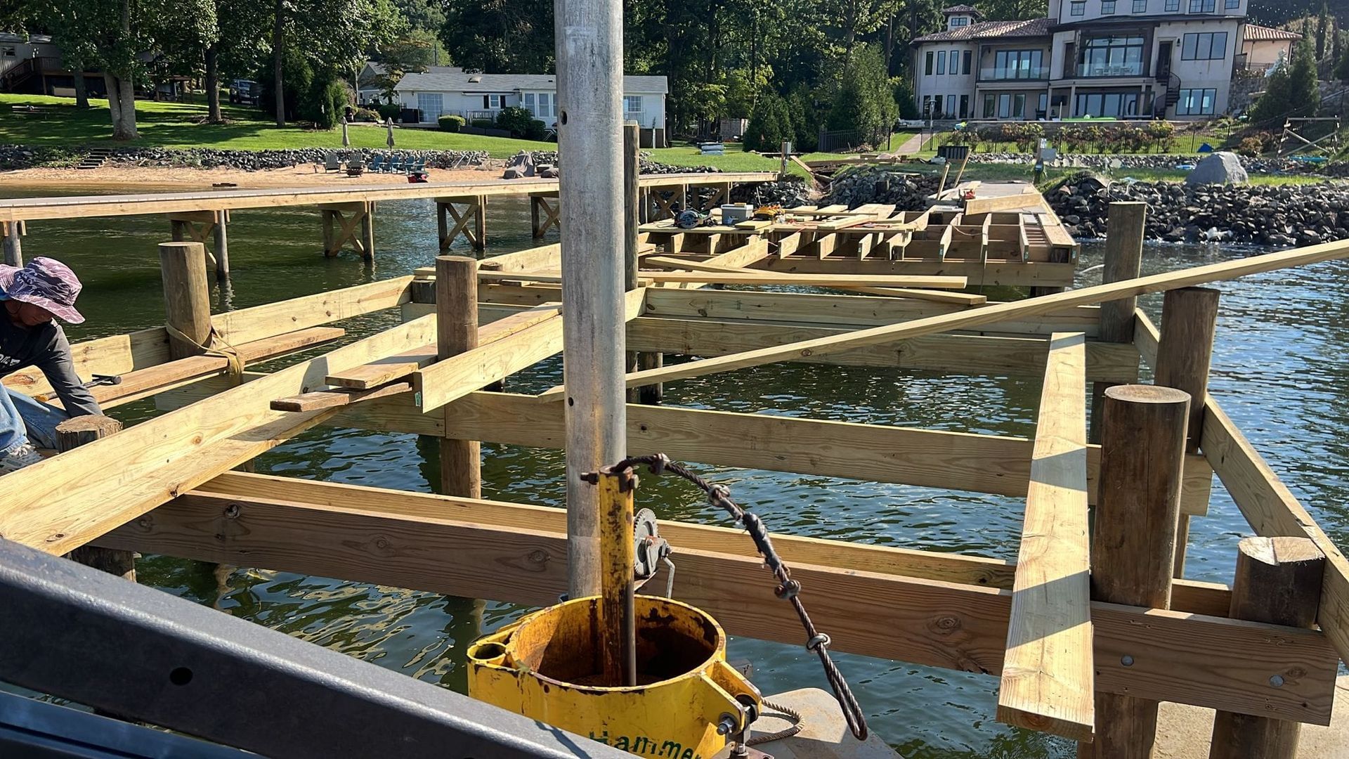 A man is working on a wooden dock in the water.