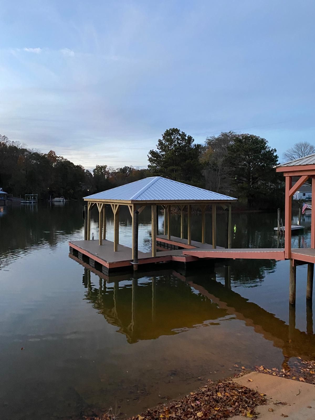 A dock with a white roof is in the middle of a lake.