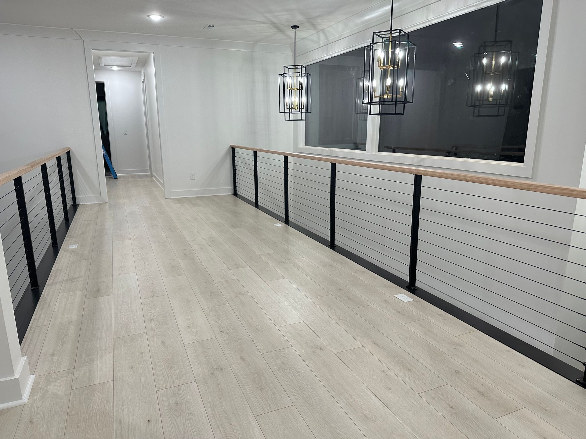 A long hallway with a railing and a large window.