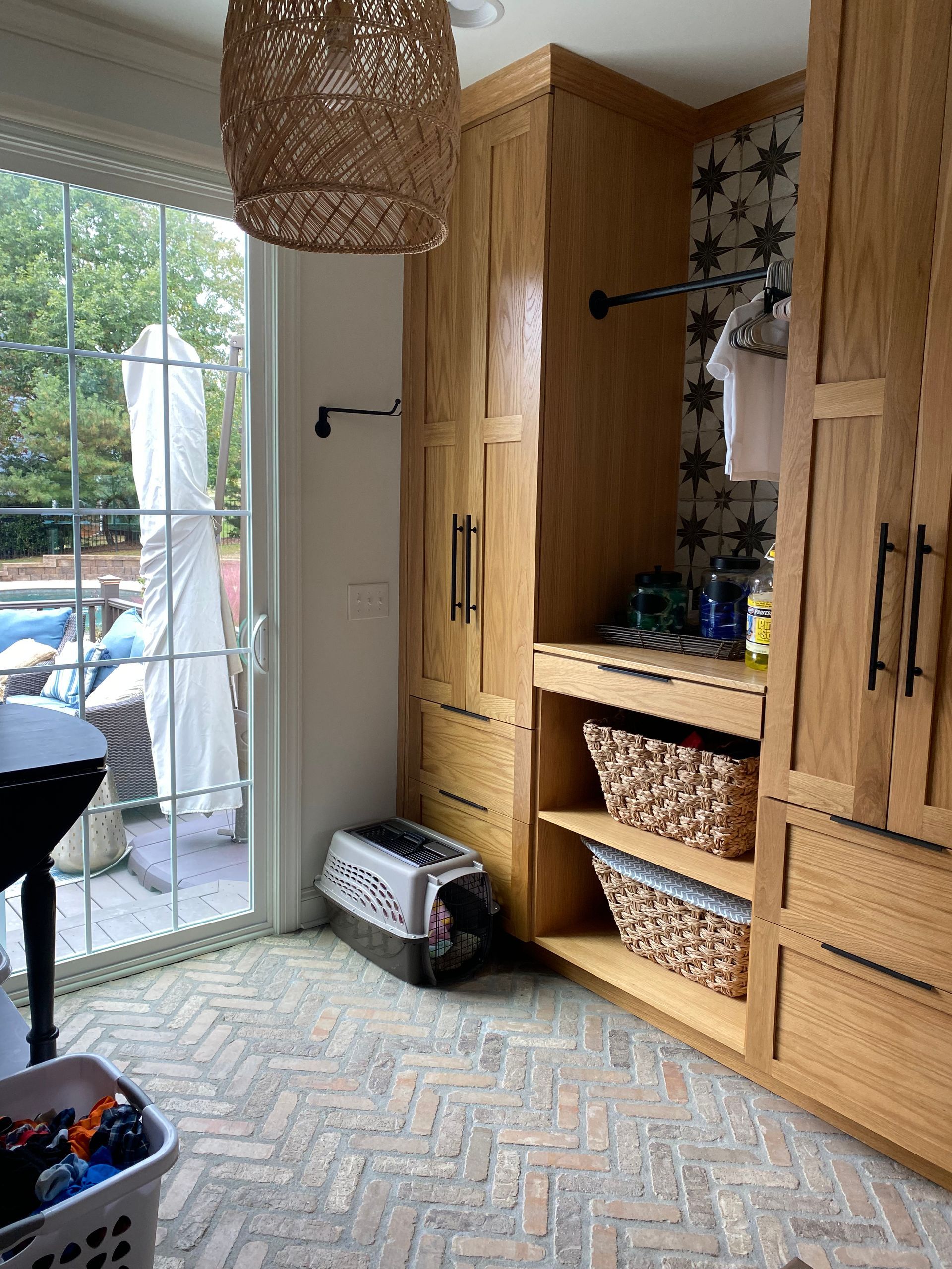 A laundry room with wooden cabinets and a sliding glass door.