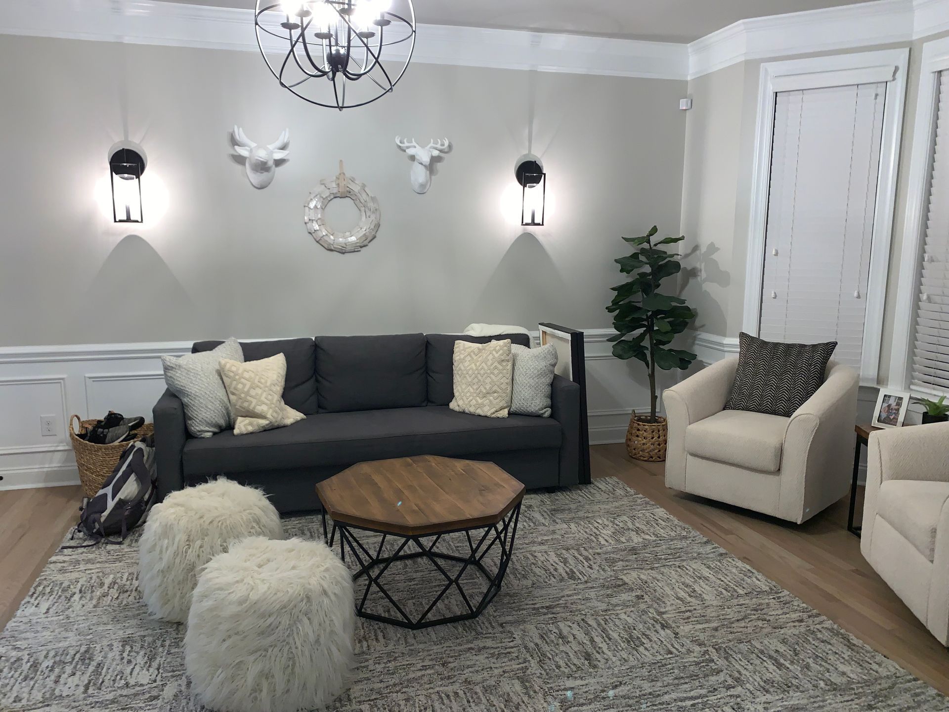 A living room with a couch , chairs , ottomans and a coffee table.
